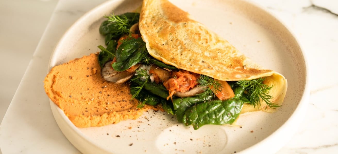 A plate of omelette with greens and filling